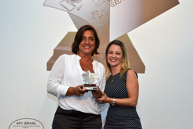 À esquerda, a Gerente de hotelaria da Tarkett Syomara Camargo recebe o prêmio de Gabriella Spinola, Diretora de Compras da rede AccorHotels pela categoria Pisos/Revestimentos