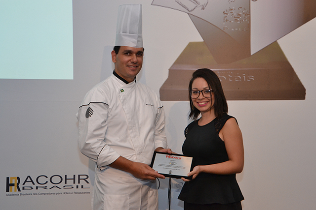 Na foto o Chef de Cozinha William Carvalho recebeu a placa de homenagem em nome da APC Brasil. A homenagem foi entregue pela repórter da Revista Hotéis Raiza Santos